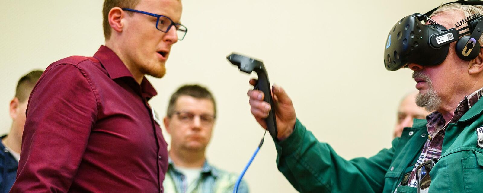 Eine Person testet eine VR-Brille zusammen mit einer anderen Person, die ein Programm auf dem Tablet überprüft und Anweisungen gibt.