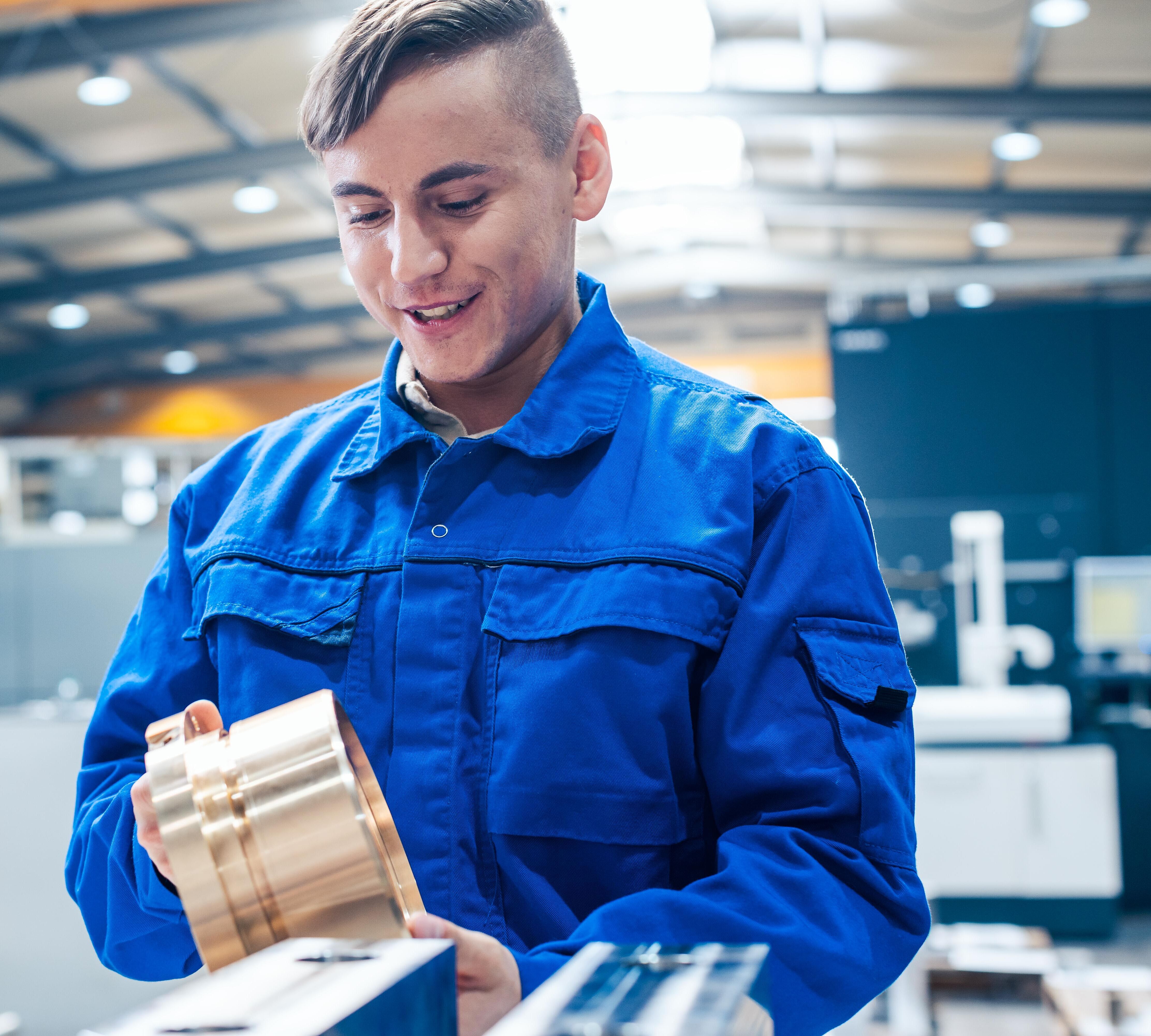 Auszubildender in der Metallverarbeitung betrachtet zufrieden ein Werkstück
